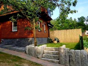 Cabaña de madera con pared de piedra frente a una casa en Alpakowy raj en Nowy Targ