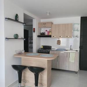 a kitchen with a counter and two black stools at Apartamento Tranquilo para Descansar in Sincelejo