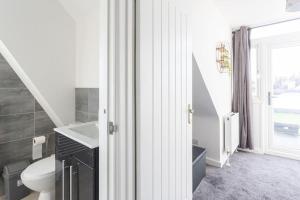 een badkamer met een toilet, een wastafel en een raam bij 2 bed apartment near the beach in Southend-on-Sea