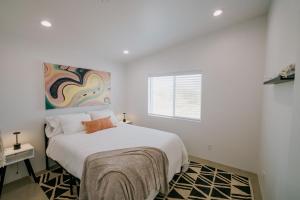 a white bedroom with a bed and a window at Coyote Tracks - A Modern Desert Experience in Joshua Tree