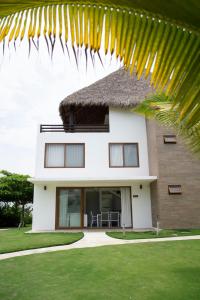 a white house with a thatch roof at Villas La Mar in Monterrico