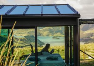 a woman sitting on a bed in a window with a laptop at Pōhue PurePod in Purau
