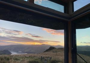 a view of a sunset from a house window at Pōhue PurePod in Purau +2 photos