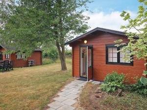 a small red cabin with a door in a yard at Two-Bedroom Holiday home in Stubbekøbing 1 in Stubbekøbing