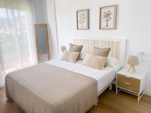 a white bedroom with a large white bed with pillows at Ítaca Apartment Peñiscola in Peñíscola