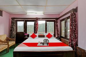 a bedroom with a bed with red pillows on it at Hotel O Hema Holiday Home in Manāli +24 photos