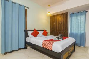 a bedroom with a large bed with blue curtains at Super OYO Broholic Hotels Near Botanical Garden in Hyderabad