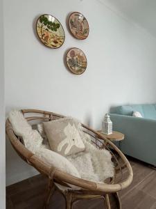 une chaise en osier avec un oreiller et des assiettes sur un mur dans l'établissement Casa dos Avós, à Vila Nova de Milfontes