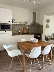 a kitchen with a wooden table and white chairs at Casa dos Avós in Vila Nova de Milfontes