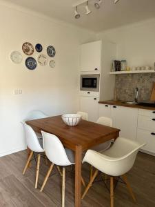 a kitchen with a wooden table and white chairs at Casa dos Avós in Vila Nova de Milfontes