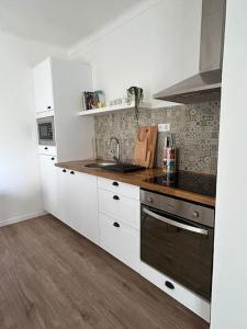 a kitchen with white cabinets and a wooden floor at Casa dos Avós in Vila Nova de Milfontes