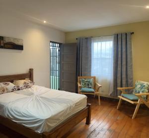 a bedroom with a bed and two chairs and a window at Casa Pitahaya in San José