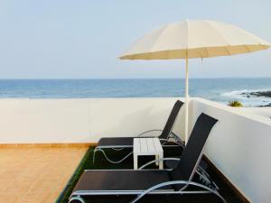 2 stoelen en een parasol op een balkon met uitzicht op de oceaan bij Vista al Mar Fuerteventura in Puerto del Rosario