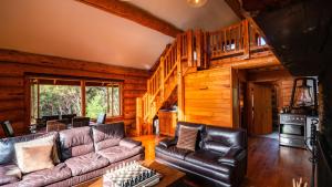 una sala de estar con muebles de cuero en una cabaña de madera en Cascade Creek Retreat, en Milton