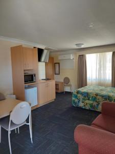 All Seasons Motor Lodge في دوبو: غرفة الفندق مع سرير وطاولة ومطبخ