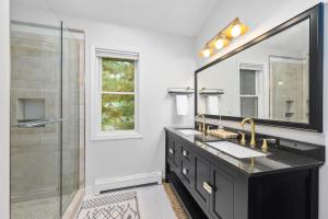 ein Bad mit einem Waschbecken, einem Spiegel und einer Dusche in der Unterkunft Gorogeous Chic 2BDR Renovated Home near Downtown Sleeps 6 843 in Traverse City