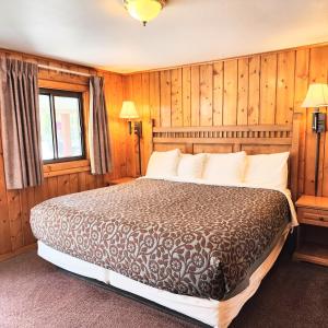 a bedroom with a large bed in a room with wooden walls at Canyon Motel in Hot Sulphur Springs