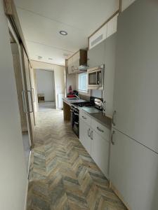 cocina con electrodomésticos blancos y suelo de madera en Emma's Pad at Hoburne Naish - New Forest - Wheel chair Accessible with wetroom and ramp en Highcliffe