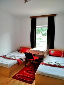 a room with three beds and a chair and a window at Apartman ASI in Mostar