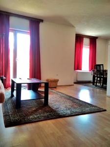 a living room with a table and red curtains at Apartman ASI in Mostar