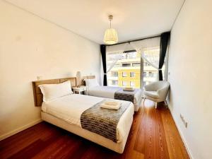 a bedroom with a bed and a chair and a window at Luz Benfica Apartment in Lisbon