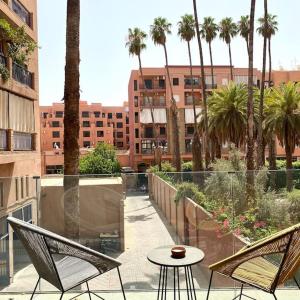 een balkon met een tafel en stoelen en palmbomen bij 2 bed apartment with Rooftop pool & gym downtown marrakech in Marrakesh