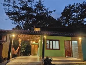 una casa con una fachada verde por la noche en CASA PRUMIRIM en Ubatuba