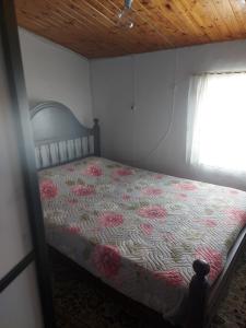a bedroom with a bed with a floral comforter and a window at o Roxo in Castelo de Vide