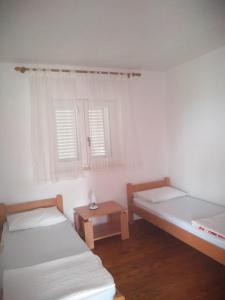 two beds in a room with a table and two windows at Apartments with a parking space Njivice, Krk - 14932 in Njivice