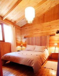 1 dormitorio con 1 cama grande en una cabaña de madera en Cabañas Alegria Cajón del Maipo, en San José de Maipo