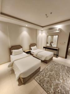 una camera d'albergo con due letti e uno specchio di المهيدب للوحدات السكنيه -رابغ a Rabigh