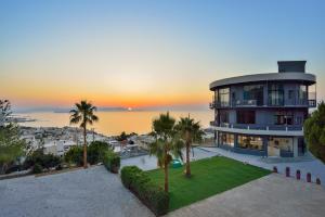 a large house with palm trees in front of a sunset at Loucerna Suites Chania in Chania Town