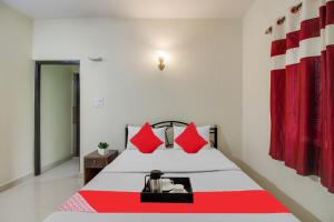 a bedroom with a large bed with red pillows at OYO 92630 Bharat Holiday Home in Saligao