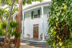 a white house with a wooden door and a porch at Dancing Palms in Key West