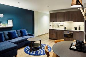 - un salon avec un canapé bleu et une table dans l'établissement Residence Inn by Marriott London Bridge, à Londres