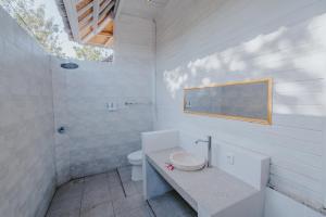 uma casa de banho branca com um lavatório e um WC em Paluh Beach Huts em Nusa Lembongan
