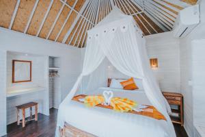 ein Schlafzimmer mit einem weißen Bett mit Baldachin in der Unterkunft Paluh Beach Huts in Nusa Lembongan