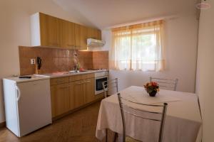 a kitchen with a table and a white refrigerator at Apartments by the sea Supetarska Draga - Gornja, Rab - 21380 in Rab