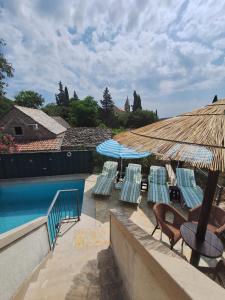 a pool with chairs and umbrellas next to a swimming pool at Luxury villa with a swimming pool Skrip, Brac - 17350 in Postira