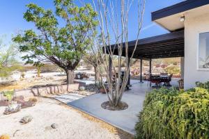 a house with a patio with a table and a tree at The Outpost Joshua Tree: Hot Tub, GameRoom, JTNP in Joshua Tree