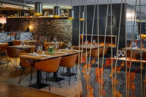 a restaurant with wooden tables and chairs and a fireplace at Hotel U14, Autograph Collection in Helsinki