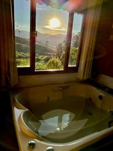y baño con bañera y ventana. en Pousada Chales Joao de Barro, en Visconde De Maua