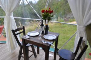 glamping casa blanca في جوتافيتا: طاولة مع كرسيين و مزهرية عليها زهور