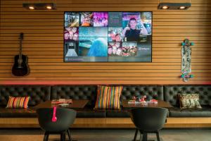 a restaurant with a couch and a tv on the wall at Moxy Frankfurt Airport in Frankfurt/Main