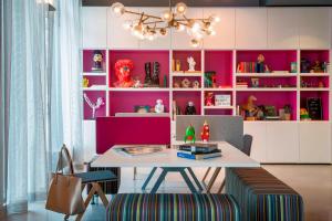 a dining room with a table and a pink wall at Moxy Frankfurt Airport in Frankfurt/Main