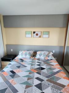 a bed with a quilt on it in a bedroom at Apartamento com Garagem Cabo Frio in Cabo Frio