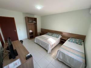 a hotel room with two beds and a television at Hotel Vila ÁguaMar in Itapoa