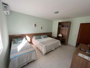 a hotel room with two beds and a desk at Hotel Vila ÁguaMar in Itapoa