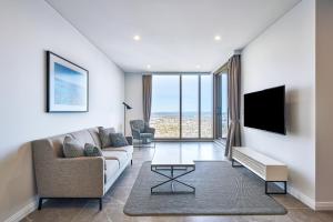 een woonkamer met een bank en een tv bij Meriton Suites George Street, Parramatta in Sydney