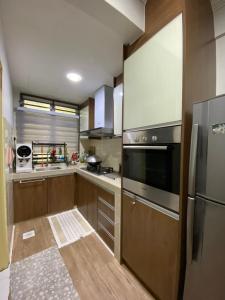 een keuken met houten kasten en een roestvrijstalen koelkast bij Homestay Hana Senawang in Seremban